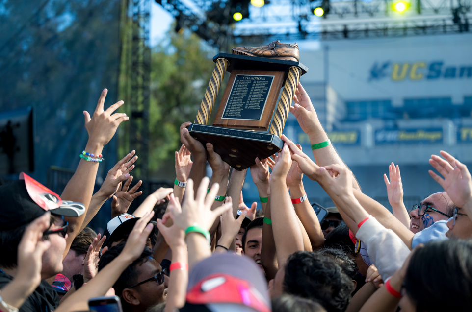 Hands reaching up towards the Golden Shoe Trophy